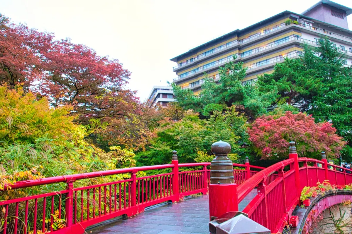 Red bridge and hillside buildings in Arima Onsen during autumn