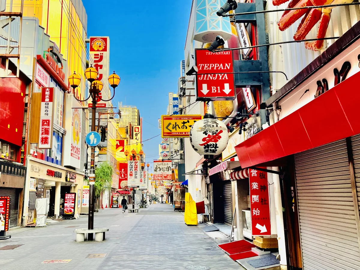 Restaurant signs and storefronts along a Dotonbori street in daylight