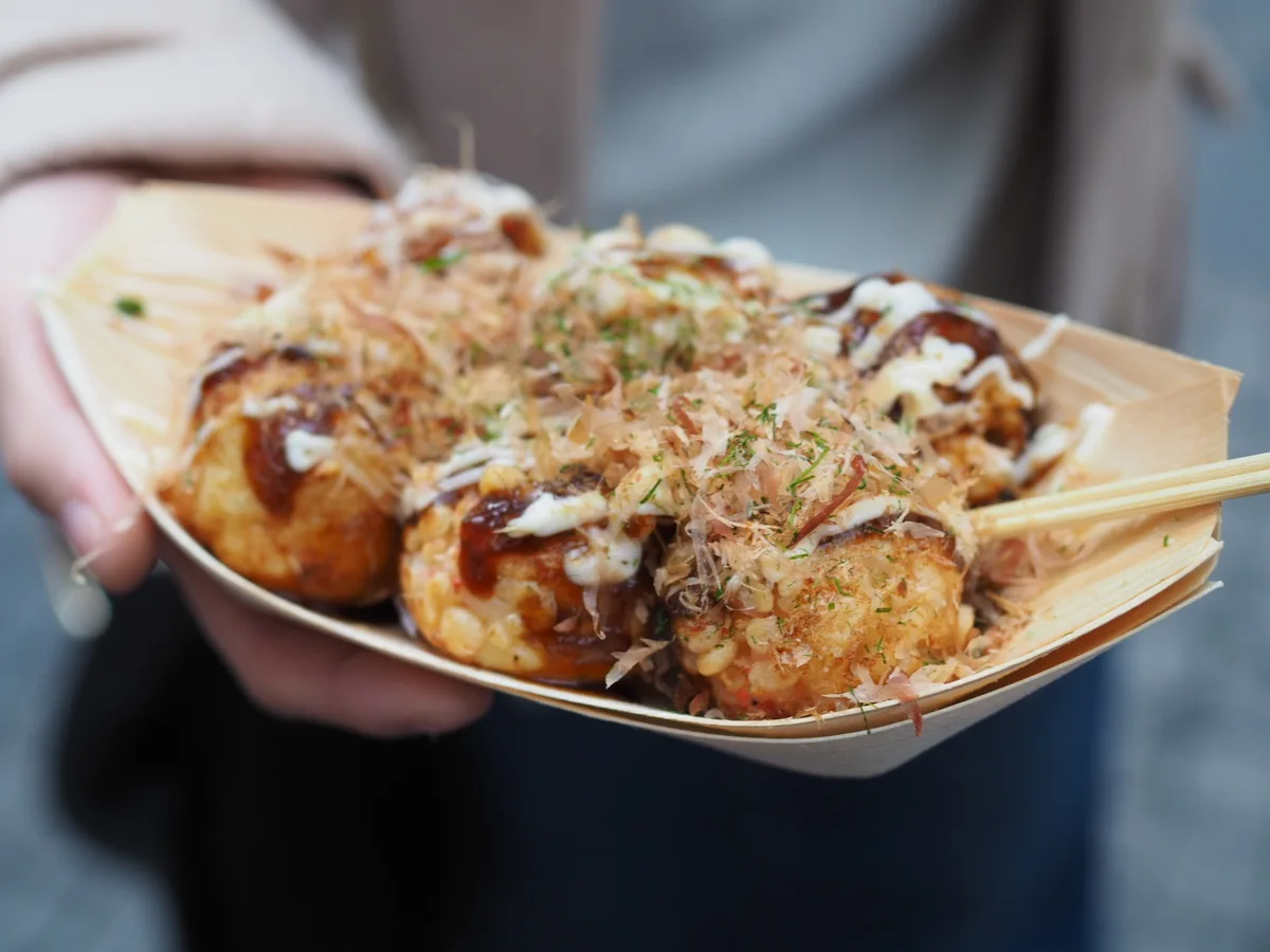 Illustrative photograph of takoyaki topped with sauce, mayonnaise and bonito flakes