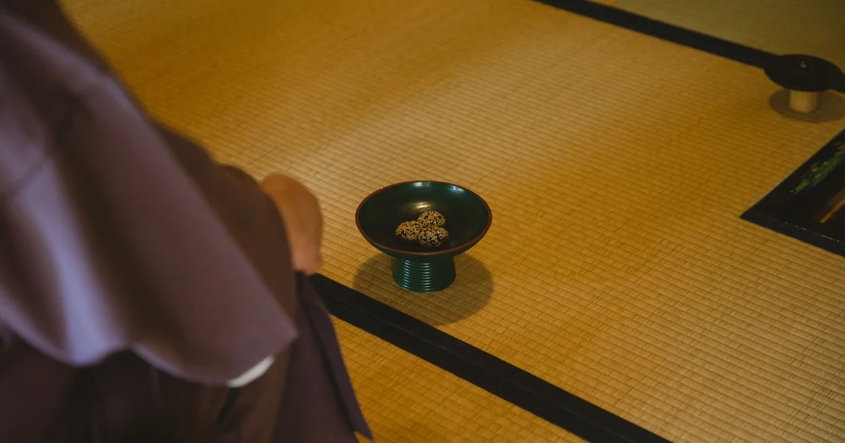 A person in kimono seated beside wagashi on tatami