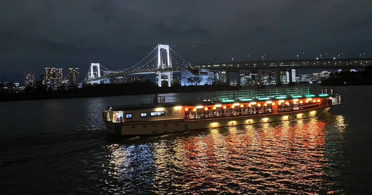 A lantern-lit yakatabune beneath Rainbow Bridge at night