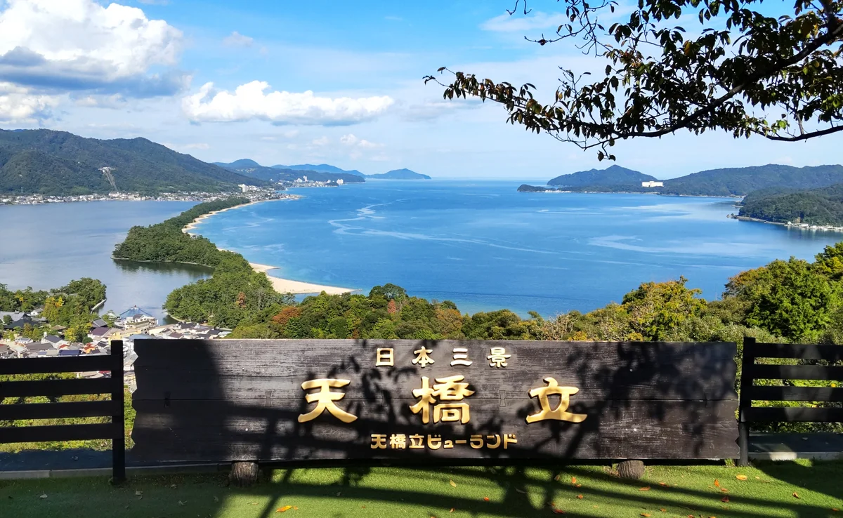 Amanohashidate sandbar and blue bays seen beyond a wooden lookout sign