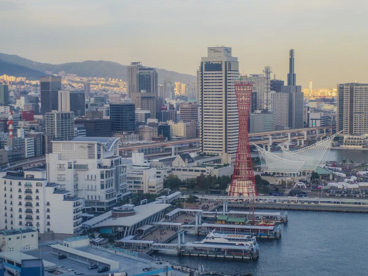 Kobe Port Tower, waterfront buildings and moored sightseeing boats, with the city and hills behind them