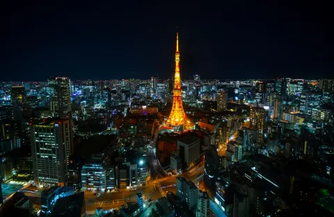 Tokyo Tower lit up orange above the glittering night skyline of the city