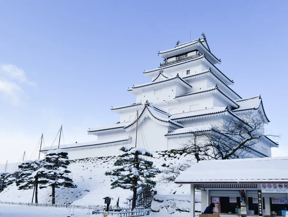 Tsuruga Castle in Aizu-Wakamatsu rising above deep snow beneath a pale blue sky