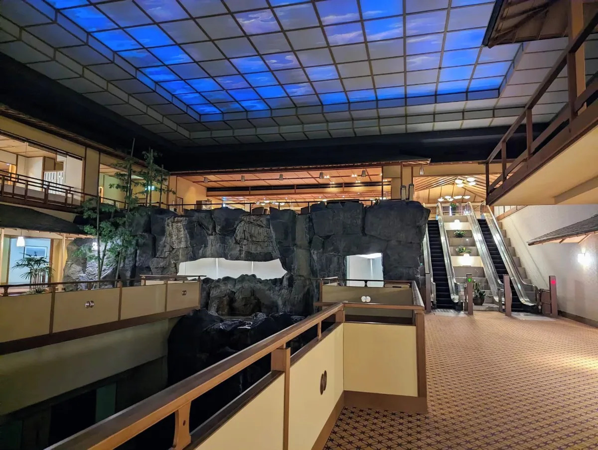 Hojoen's atrium and rockwork beneath blue ceiling lighting, with a walkway and escalator beside them