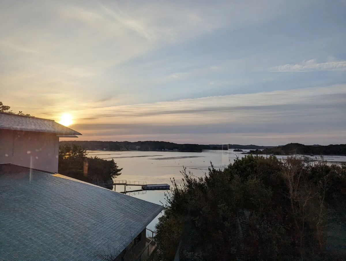 Ago Bay and low sunlight visible beyond the hotel's tiled roofs