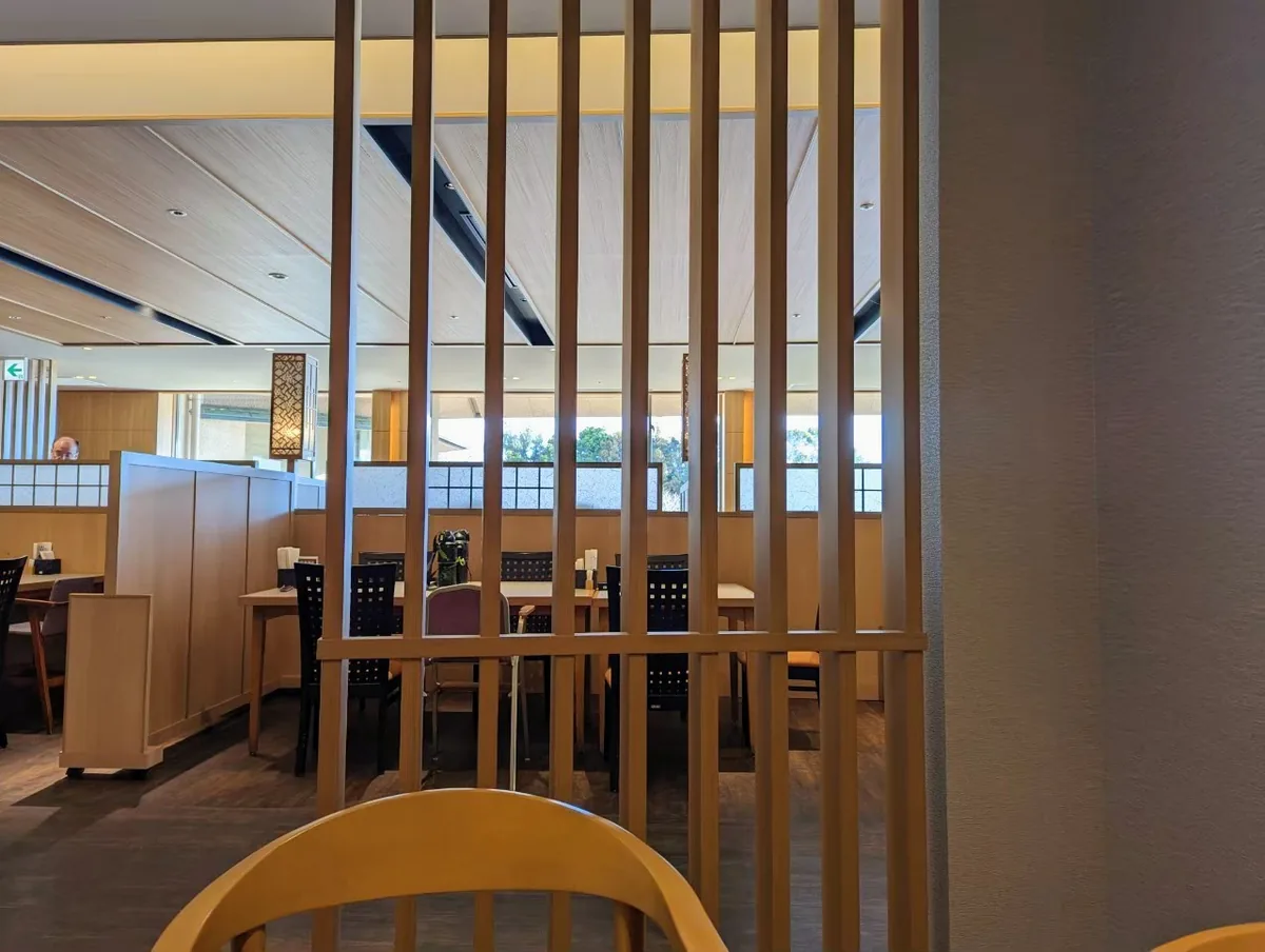 Tables and chairs in a dining venue, separated by wooden screens and vertical slats