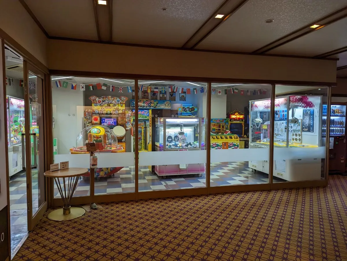 A glass-fronted hotel game corner with arcade and prize machines inside