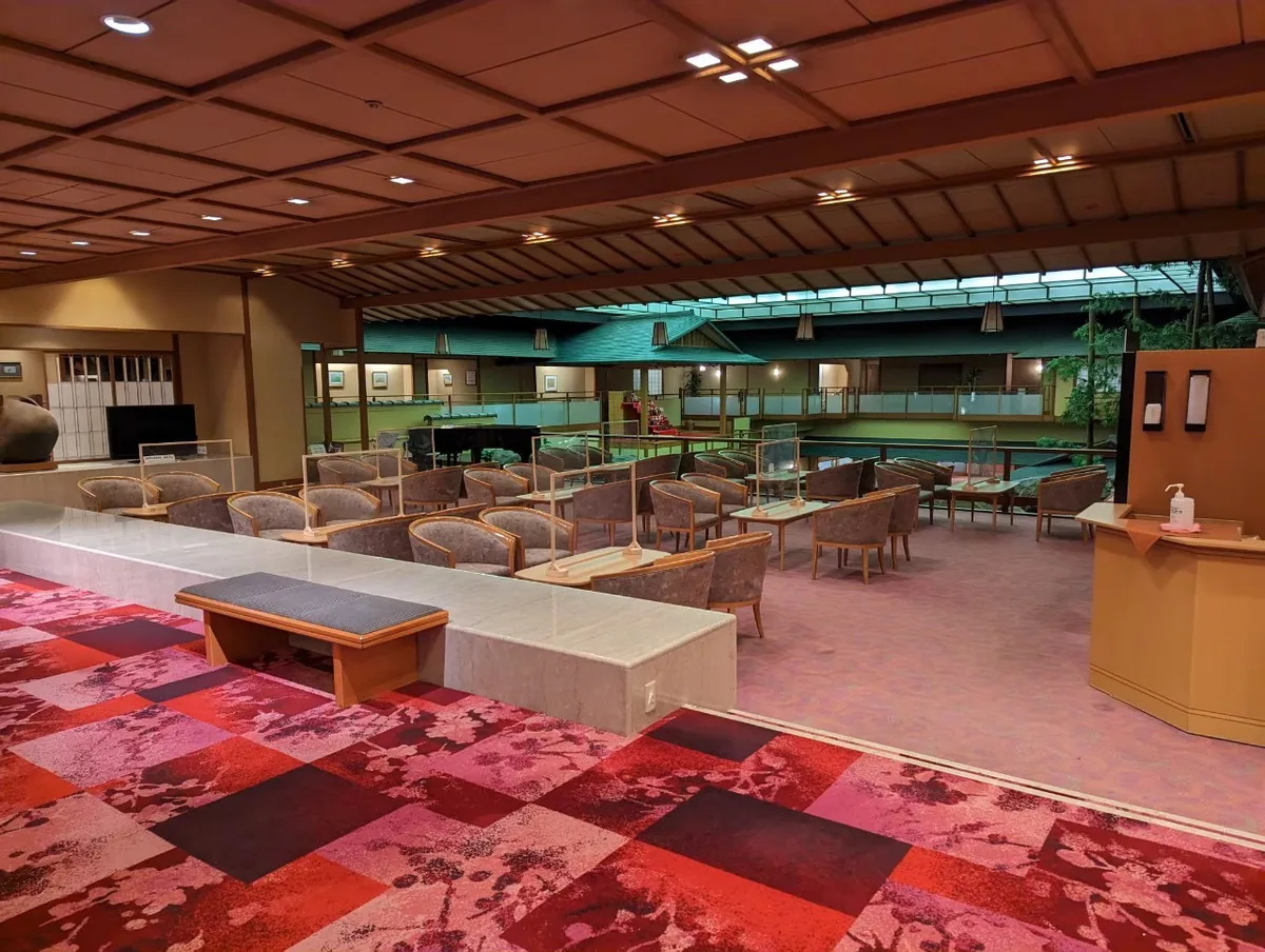 A broad hotel lounge with rows of chairs beneath a wooden ceiling