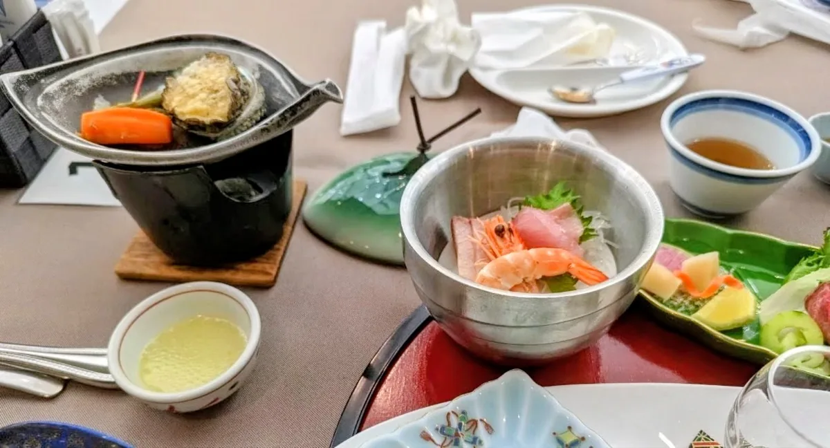 Our dinner table with abalone on a tabletop hotplate, sashimi in a metal bowl and small side dishes