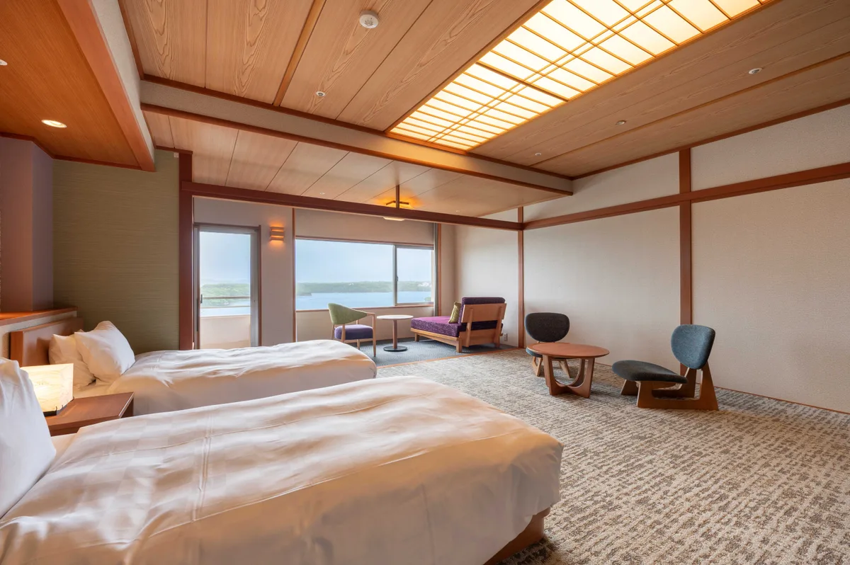 An official Rankei room example with two beds, chairs beside the windows and a view of Ago Bay