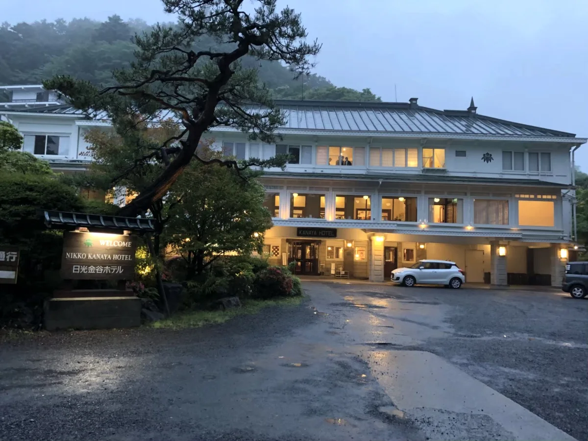 Nikko Kanaya Hotel with illuminated windows and a tree in front of the building at dusk.