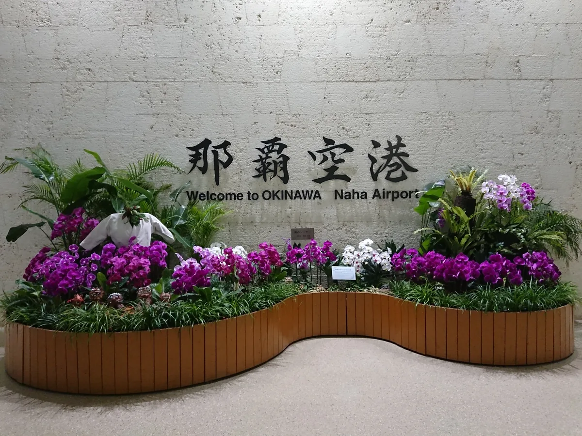Naha Airport welcome sign above a display of orchids