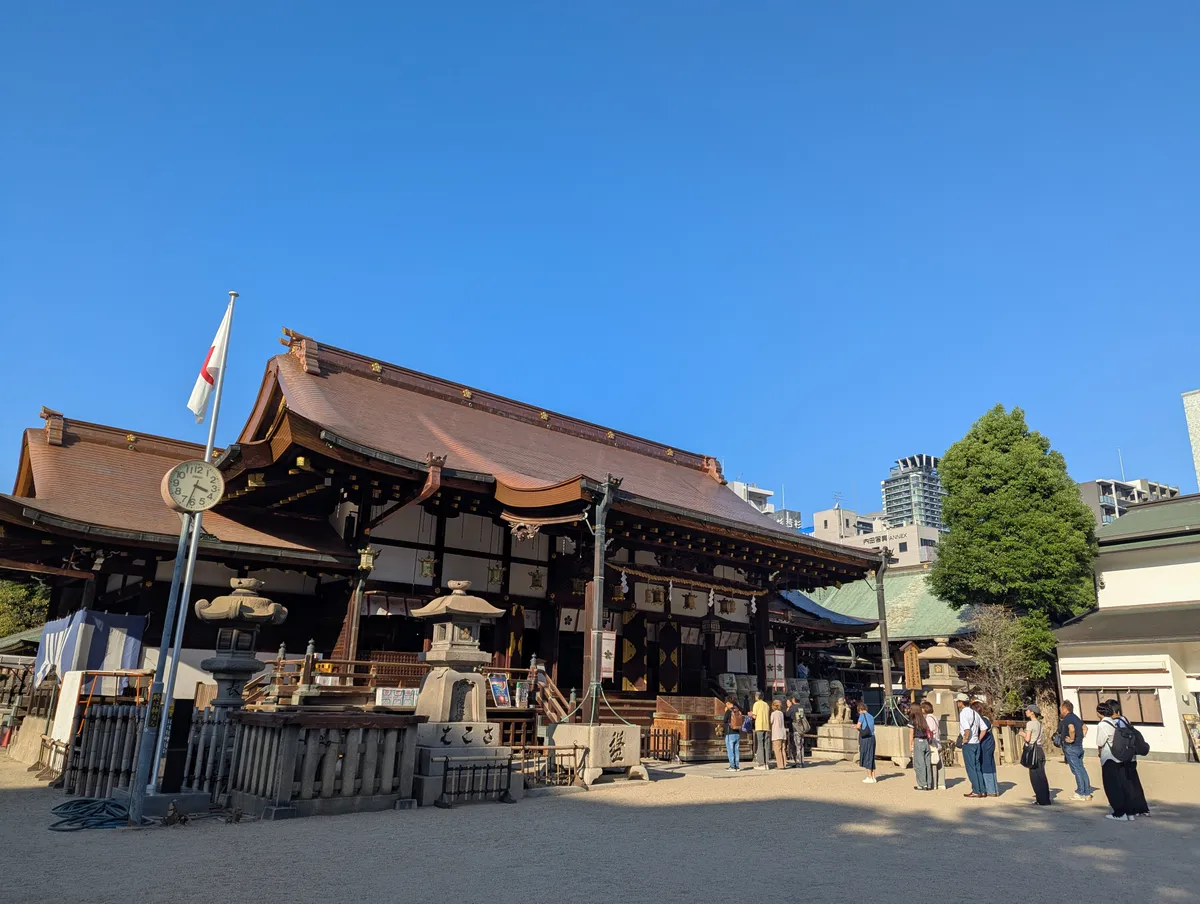 Osaka Tenmangu's wooden worship hall with modern Osaka buildings behind its roof