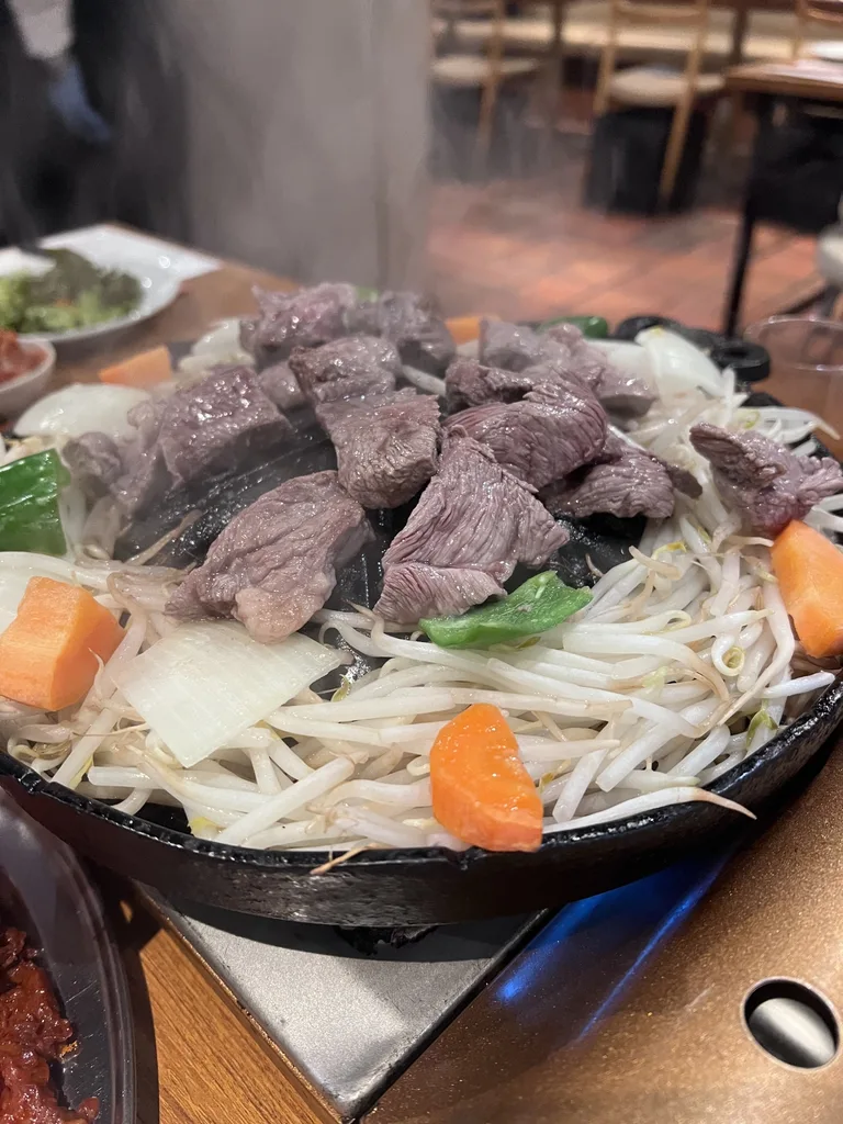 Lamb and vegetables cooking on a hot jingisukan grill