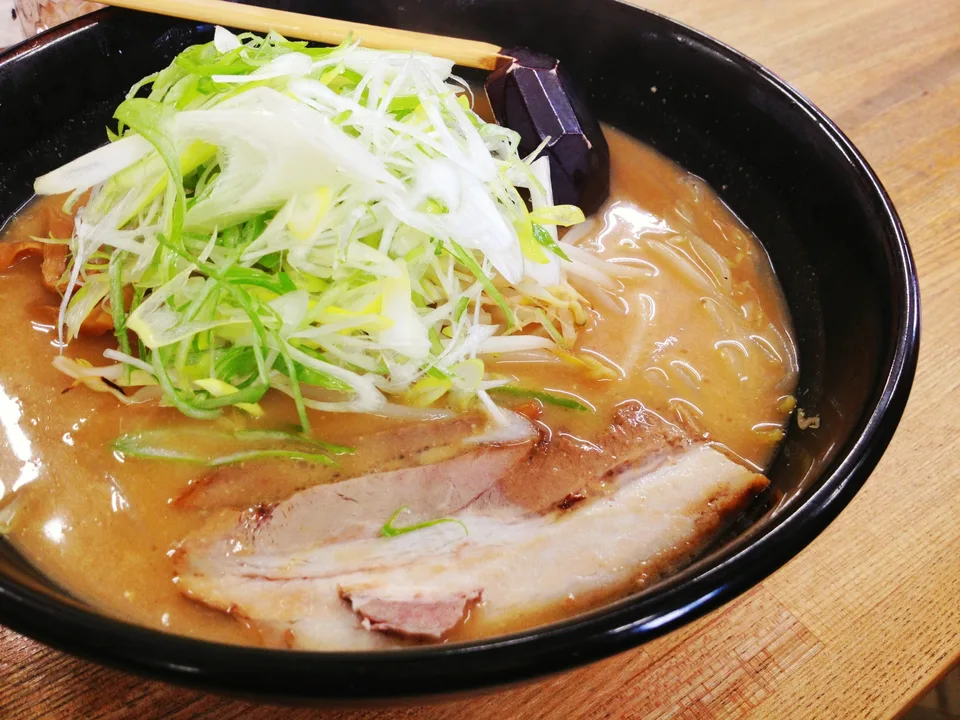 A bowl of miso ramen topped with sliced pork and scallions
