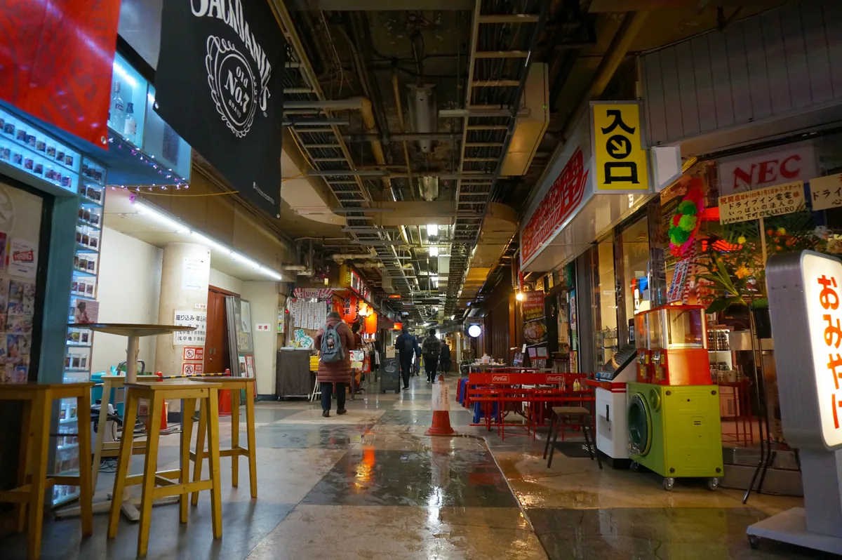 A covered Tokyo dining alley with small restaurants and bright signs